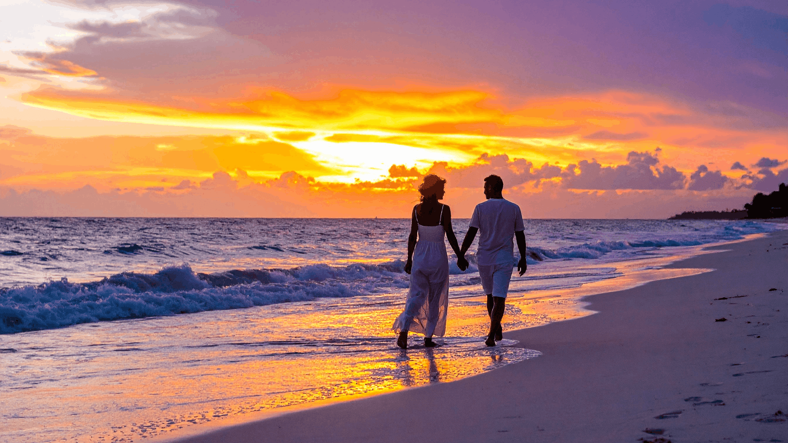 Couple walking on a golden Goa beach at sunset – popular Goa honeymoon packages 2026